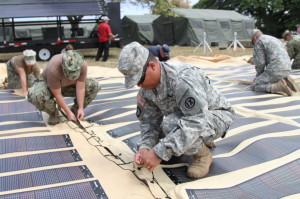 Soldiers becket lace the solar shade canopy together during the setup of a humanitarian aid and disaster relief event for the Rim of the Pacific training exercise at Ford Island, Hawaii, in July 2014. The solar shade has the potential to provide enough energy for several days of continuous, 24-hour use. Twenty-two nations, more than 40 ships and submarines, about 200 aircraft and 25,000 personnel participated in the exercise. Photo Credit: Staff Sgt. Kyle J. Richardson, USARPAC PAO